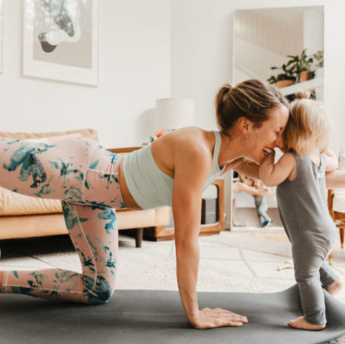 woman doing a barre3 class on yoga mat with baby