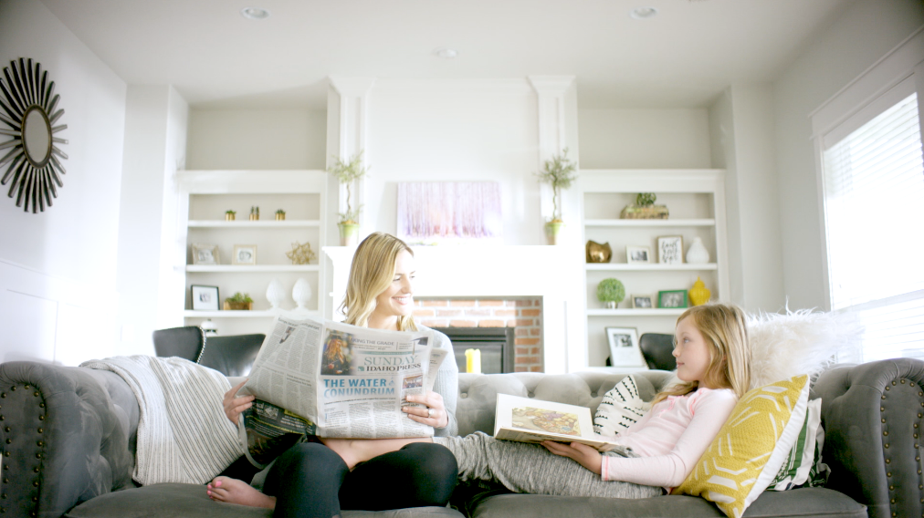 Woman with daughter reading Idaho Press newspaper.